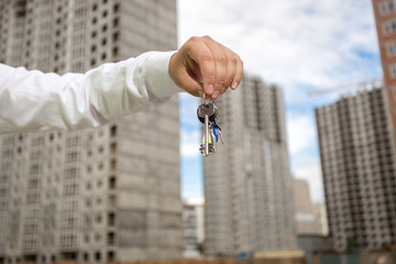 Closeup of businessman holding keys in front of new building