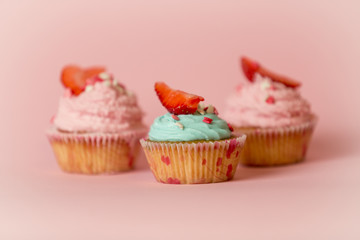 Closeup of three decorated cupcakes over pink background