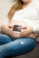 Closeup photo of pregnant woman posing with ultrasound abode image