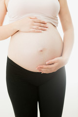 Young pregnant woman in sportswear posing on white background