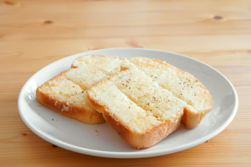 garlic butter bread and delicious dessert on white dish and wood table for breakfast or snack food in the morning at cafe or restaurant