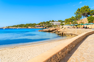 Coastal promenade along Cala Portinatx beach with azure blue sea water, Ibiza island, Spain