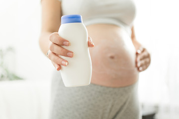 Closeup image of pregnant woman holding creme container with copy space