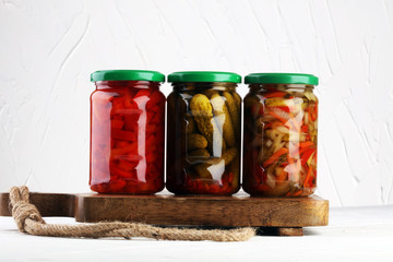 Jar with variety of pickled vegetables. Carrots, field garlic, cucumber in glas. Preserved food