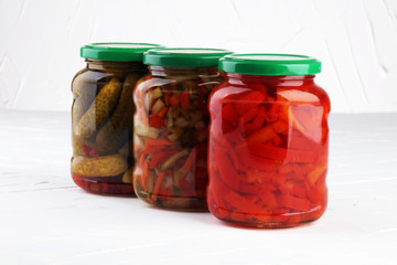 Jar with variety of pickled vegetables. Carrots, field garlic, cucumber in glas. Preserved food