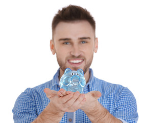 Happy young man holding piggy bank on white background
