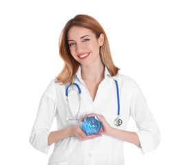 Happy young doctor holding piggy bank on white background