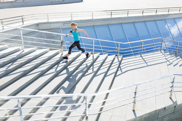 Full length shot of healthy young woman climbing up and running on stairs