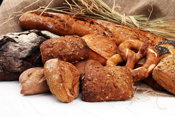 Different kinds of bread rolls on white board from above. Kitchen or bakery poster design.