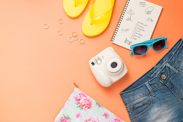 Summer traveling concept. Vacation accessories on orange background.
