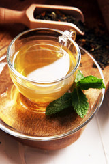 Cup with green tea on brown wooden background with mint leaves