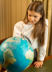 Portrait of cute schoolgirl looking at Earth globe