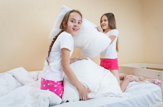 Two sisters having pillow fight on bed