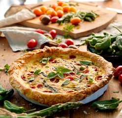  Quiche with cherry tomatoes and green asparagus on a rustic wooden table