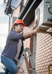 Male technician repairing outdoor air conditioning system