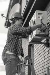 Black and white photo of young man repairing air conditioner