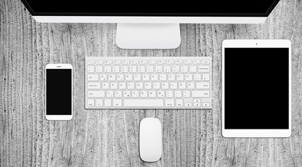 Grey wooden desk with tablet, PC and phone, top view, mockup