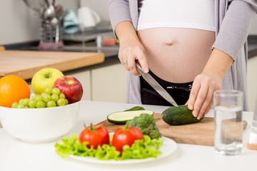 Obraz na płótnie Canvas Closeup photo of pregnant woman making salad on kitchen
