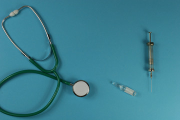Stethoscope and syringe on blue background.
