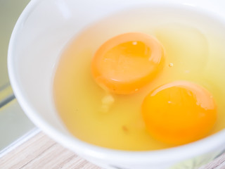 Closeup of two eggs yolk and egg white in white bowl for cooking