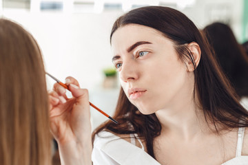 Portrait of a master in a beauty salon during the procedure. The woman doing make-up in the beauty salon to the client.