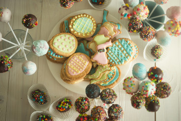 Assortment of candies, cake pops and cookies on wooden table at confectionery