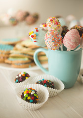 Closeup of beautiful cake pops in blue cup on wooden table
