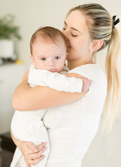 Young beautiful woman kissing her baby boy on hands