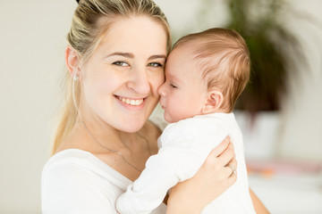 Beautiful cheerful mother embracing her 3 months old baby boy