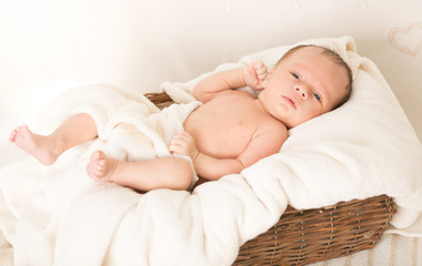 Portrait of beautiful baby boy lying in wicker basket