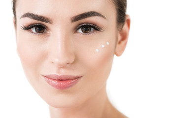 Obraz premium Happy young woman using facial cosmetics