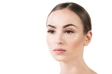 Fototapeta premium Serious beautiful girl using cosmetics for face skin