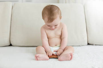 Baby boy sitting on bed and holding smartphone