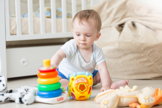 Cute baby boy assembling colorful toy tower on floor