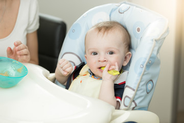 9 months baby boy with spoon sitting in highchair