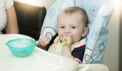 Closeup of baby sitting in highchair and holding spoon