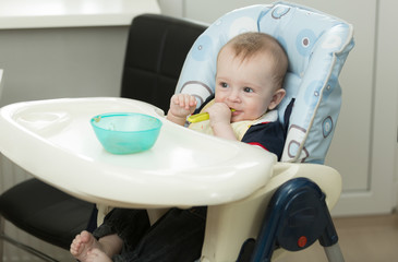 Little baby boy playing with food and dish while eating