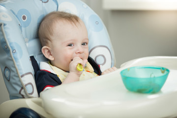 Cute smiling baby boy eating with spoon