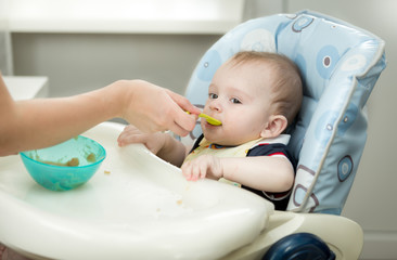 Closeup of mother giving porridge from spoon to her baby