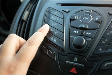 Obraz premium Closeup of female finger pressing radio button on car control panel