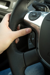 Closeup of female driver adjusting cruise control system on steering wheel