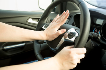 Closeup image of annoyed woman driving car and honking