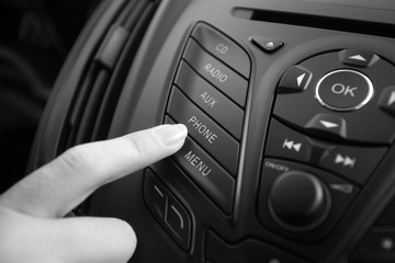 Black and white closeup photo of woman adjusting car stereo system