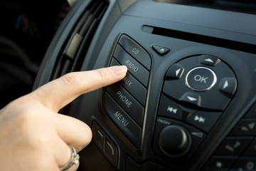 Fototapeta premium Closeup of female finger pressing radio button on car control panel