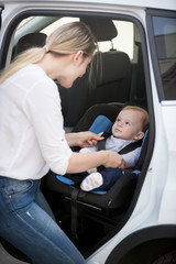 Mother seating her baby in car safety seat