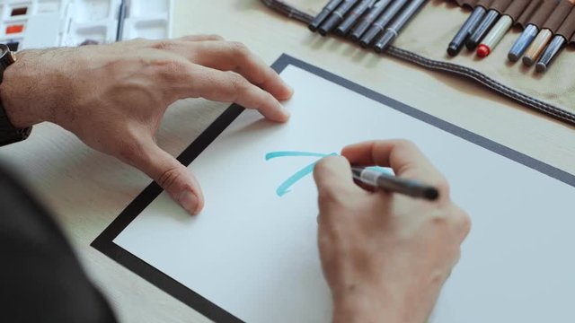 Handheld shot of designer hands writing word Travel with sea blue colored permanent marker on white a4 paper sheet