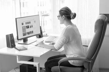 Black and white portrait of beautiful female designer working at computer