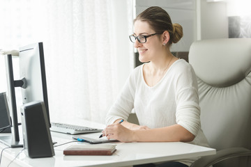 Beautiful smiling woman working at computer in home office