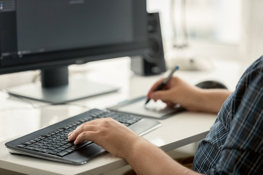 Toned photo of graphic designer using tablet and keyboard at work
