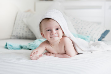 Fototapeta na wymiar 9 months old baby lying under white towel on bed